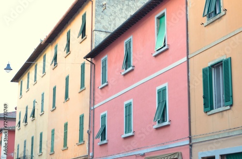 Facades of houses of different colors with windows.