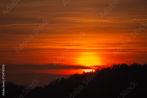 Orange solar disk seen above the forest. Wonderful sunset at the end of day © badescu