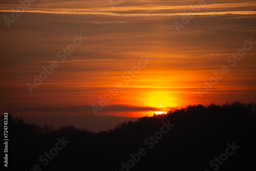 Orange solar disk seen above the forest. Wonderful sunset at the end of day © badescu