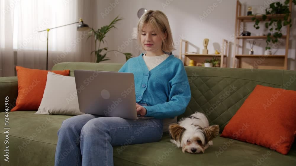 Productive lady typing on laptop with dog laying next to her Productive lady typing on laptop with dog laying next to her