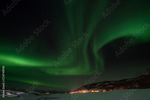 Spectacular northern lights (Aurora Borealis) dancing over a snowy landscape near Tromsø, Norway. © Ludovic Charlet