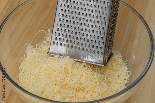 Zbliżenie na tarka kuchenna w misce i scierany na ostrych oczkach ser