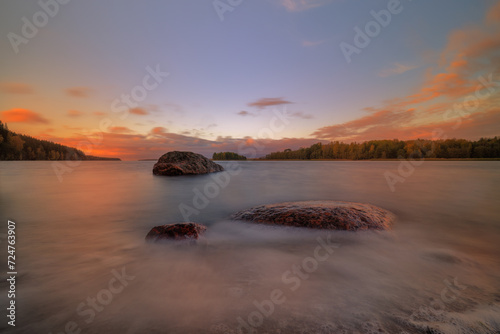 View of the coast and the Gulf of Finland in spring with stones in the water at sunset. The water is like cotton wool due to the long exposure time.