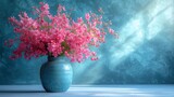  a blue vase filled with pink flowers on top of a blue tableclothed wall behind a blue vase filled with pink flowers on top of a blue table cloth.