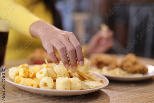 Woman eating fried chicken and snacks at home.