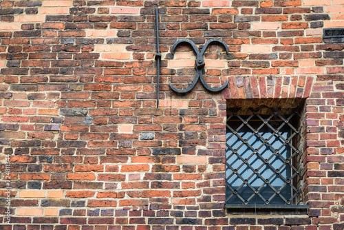 Small barred window in an old brick wallin Torun. The metal bars on the window. 