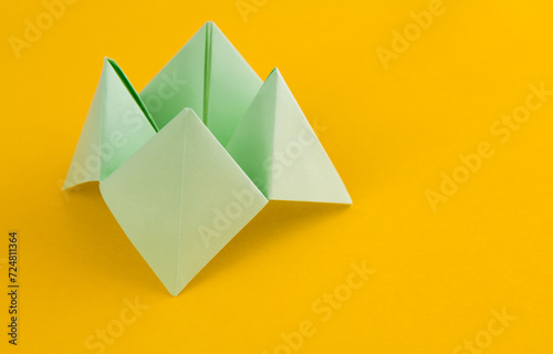Origami paper fortune on yellow background photo