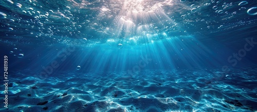Underwater bubbles allow sunlight to penetrate the azure ocean depths dark blue.  photo