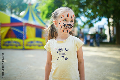 Little preschooler girl with tiger face painting outdoors photo