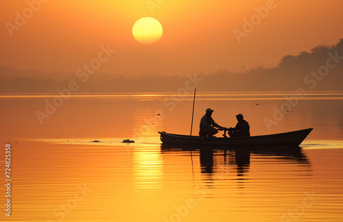two fishermens on a boat on a foggy morning at dawn