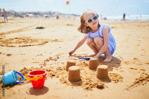 Adorable preschooler girl playing on the sand beach at Atlantic coast of Brittany, France