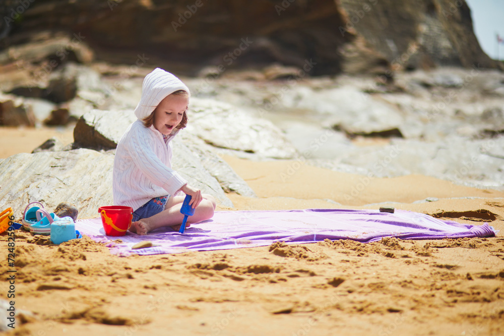 Adorable preschooler girl playing on the beach at Atlantic coast of Brittany, France Adorable preschooler girl playing on the beach at Atlantic coast of Brittany, France