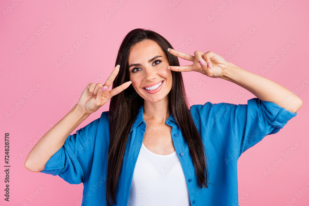 Photo of funny cheerful pretty girl with straight hairdo dressed blue shirt showing v-sign on eyes isolated on pink color background Photo of funny cheerful pretty girl with straight hairdo dressed blue shirt showing v-sign on eyes isolated on pink color background