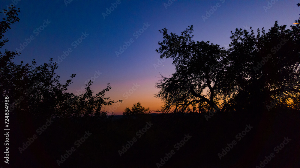 Young crescent moon on a clear sky at the end of the day in the summer