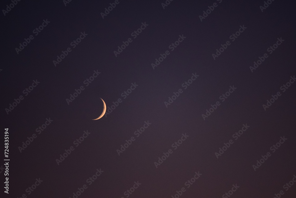 Young crescent moon on a clear sky at the end of the day in the summer Young crescent moon on a clear sky at the end of the day in the summer