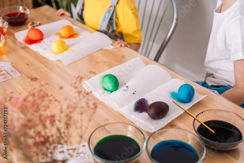 Children preparing for Easter paint eggs in different colors.