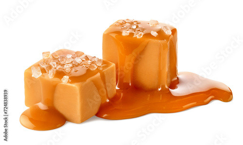 Two salty caramel candy cubes topped with caramel sauce and salt on white background photo