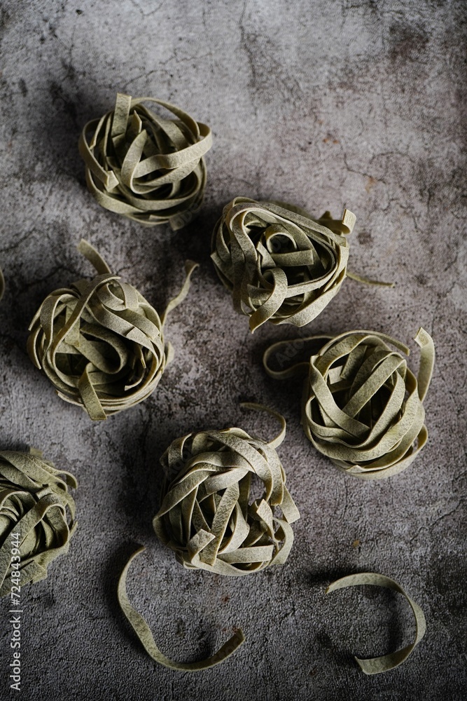 Dry raw spinach fettuccine pasta on rustic background, selective focus Dry raw spinach fettuccine pasta on rustic background, selective focus