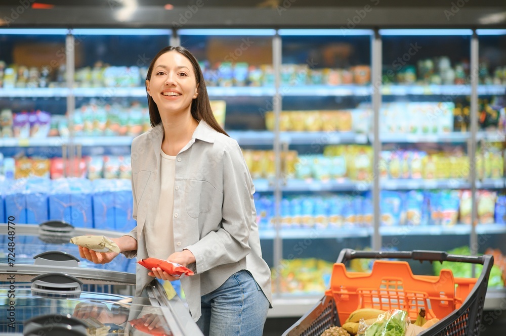 Young customer woman wear casual clothes shopping at supermaket store grocery shop buying with trolley cart choose products inside hypermarket.