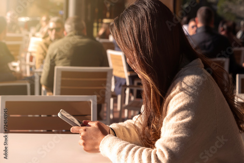A young Chinese woman uses her phone in a bar, waiting for her breakfast. © REC Stock Footage