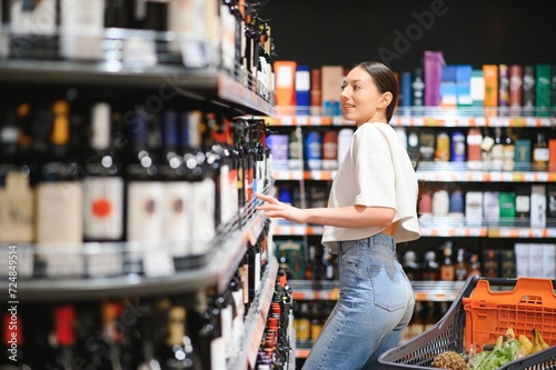 girl chooses wine in supermarket