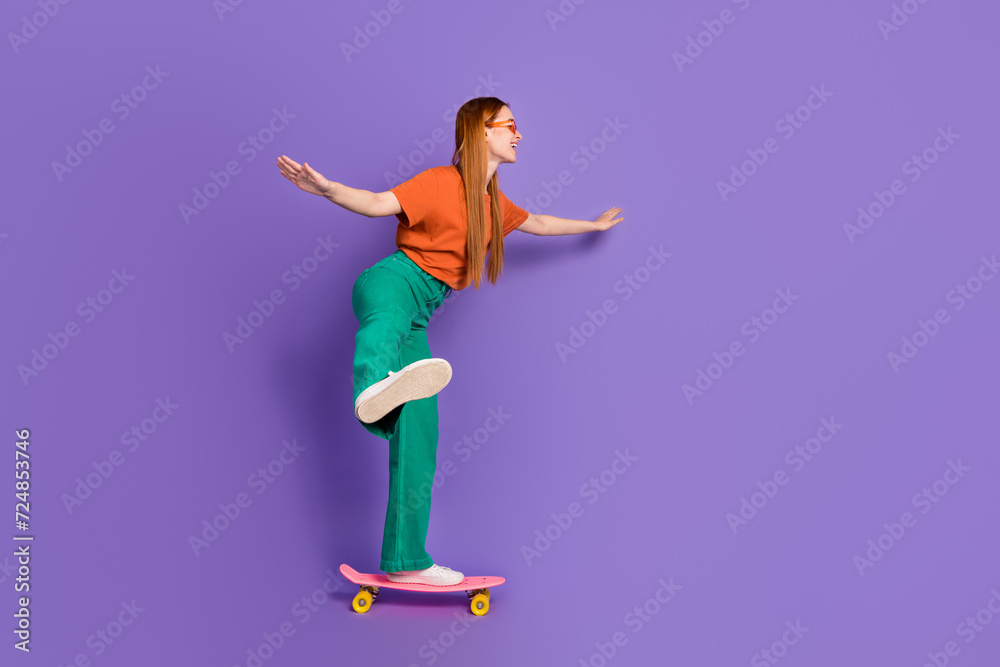 Photo of lovely pretty good mood girl dressed stylish clothes riding long board empty space isolated on purple color background