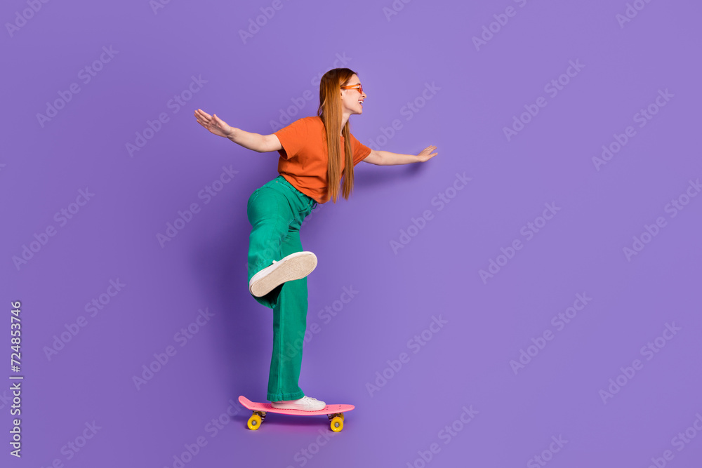 Obraz premium Photo of lovely pretty good mood girl dressed stylish clothes riding long board empty space isolated on purple color background