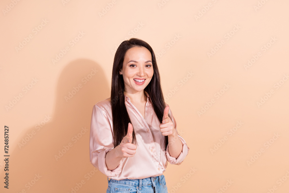Portrait of girlish coquette woman with straight hairdo dressed silk blouse indicating at you smiling isolated on beige color background Portrait of girlish coquette woman with straight hairdo dressed silk blouse indicating at you smiling isolated on beige color background