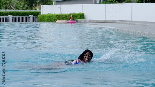 Looking good African-American women in multi-color swimsuit enjoy swimming in a private swimming pool villa.