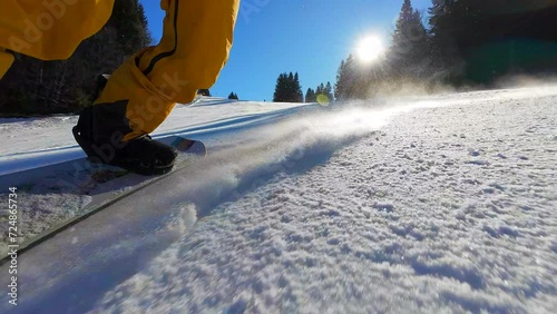 SLO MO Snowboarder making snow particles while snowboarding and making curves down the slope on a perfect sunny day