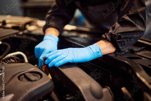 Close-up of a male mechanic checking some parts of the car, using protective gloves.