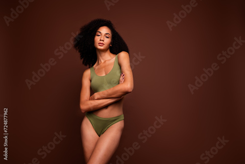 Studio no retouch photo of lovely confident lady dressed lingerie arms folded empty space isolated brown color background © deagreez