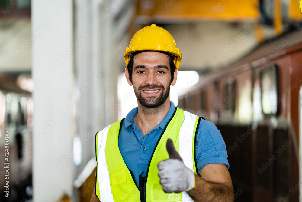 Happy male engineer wearing safety suit stands in factory and gives thumbs up appreciating work success. Happy male engineer wearing safety suit stands in factory and gives thumbs up appreciating work success.