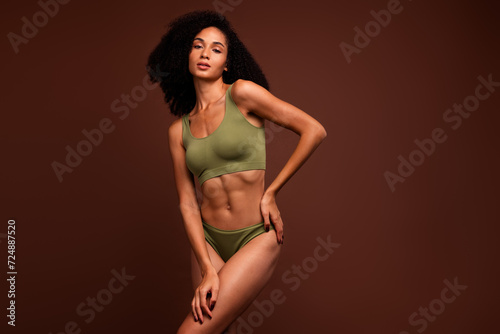 No filter photo of gentle perfect girl posing in new collection activewear promoting top and panties isolated on brown color background