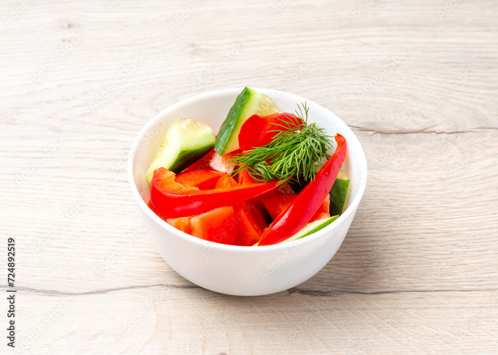 Vegetable salad of tomatoes, cucumbers and peppers on a wooden background Vegetable salad of tomatoes, cucumbers and peppers on a wooden background