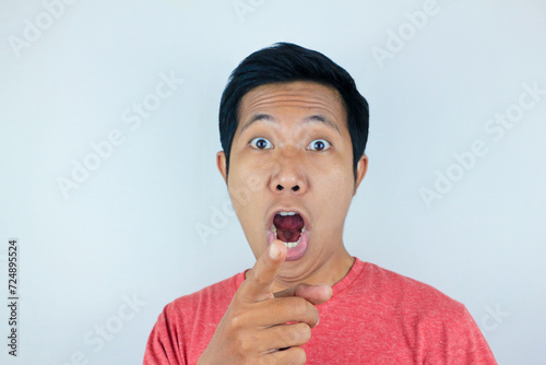 funny facial expression of asian man shocked and surprised while looking and pointing at the camera photo