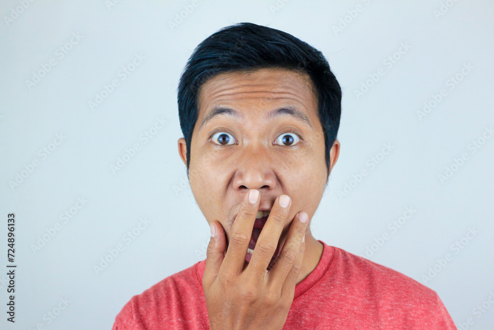 funny expression of shocked and surprised Asian man wearing a red t-shirt looking at the camera funny expression of shocked and surprised Asian man wearing a red t-shirt looking at the camera