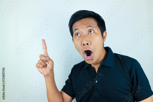 funny facial expression of asian man shocked and surprised while pointing at up side photo