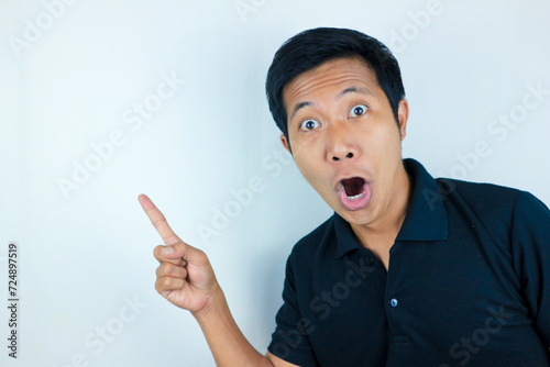 funny facial expression of asian man shocked and surprised while pointing at right side photo