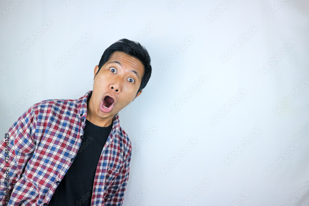 funny expression of shocked and surprised Asian man in flannel shirt isolated on white background funny expression of shocked and surprised Asian man in flannel shirt isolated on white background