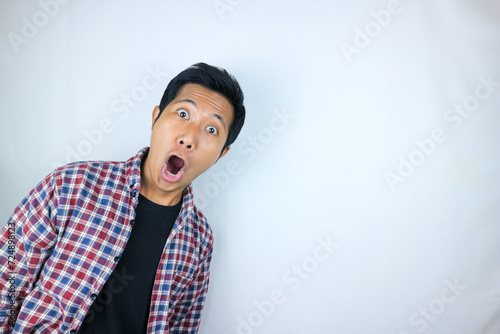funny expression of shocked and surprised Asian man in flannel shirt isolated on white background photo