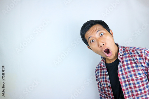 funny expression of shocked and surprised Asian man in flannel shirt isolated on white background photo