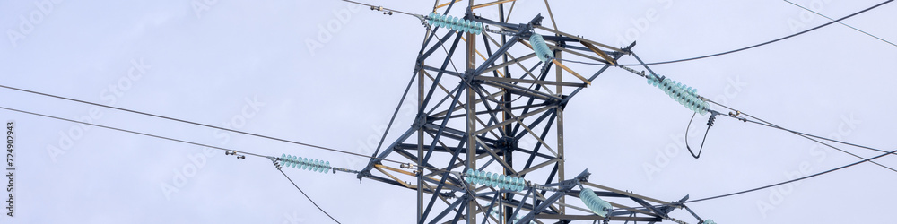 banner is 4x1 Part of an electric line support with insulators and wires on a blue sky background