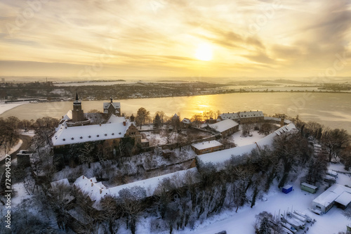 Aussicht auf das Schloss Seeburg mit Sonnenuntergang über dem Süßen See im Winter