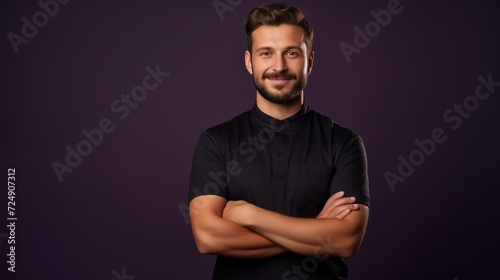 Confident young handsome barber wearing uniform pointing with hands at side isolated on purple