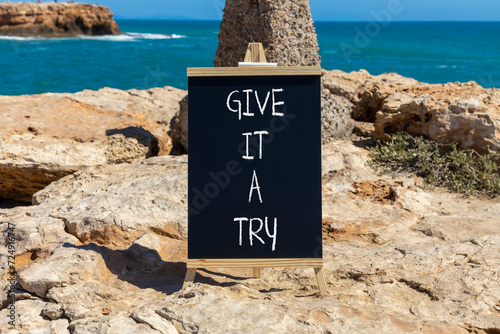 Give it a try symbol. Concept word Give it a try on beautiful black chalk blackboard. Beautiful red stone blue sea background. Business give it a try concept. Copy space.
