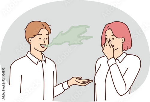 Fototapeta Naklejka Na Ścianę i Meble -  Woman covers nose with hand, feels discomfort communicating with man due to bad breath. Guy with bad breath not brushing teeth causes problems for others after refusing toothpaste