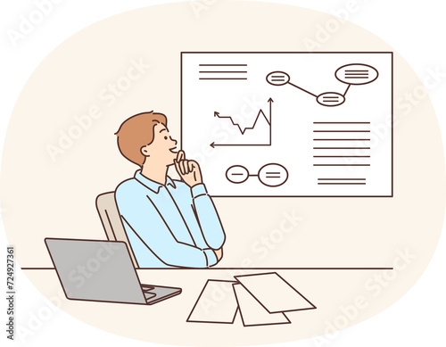 Man corporate manager happily looking at growing charts of increasing profits. Guy manager is sitting at table with laptop studying business data on increase in number of customers