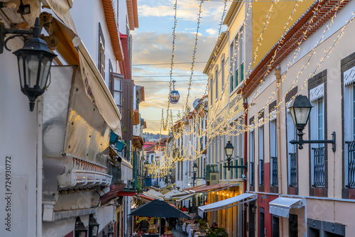 A cable car gondola to the town of Monte passes over the famous Rua de Santa Maria narrow street of cafes, colorful doors and shops in the historic medieval old town of Funchal, Madeira Portugal.