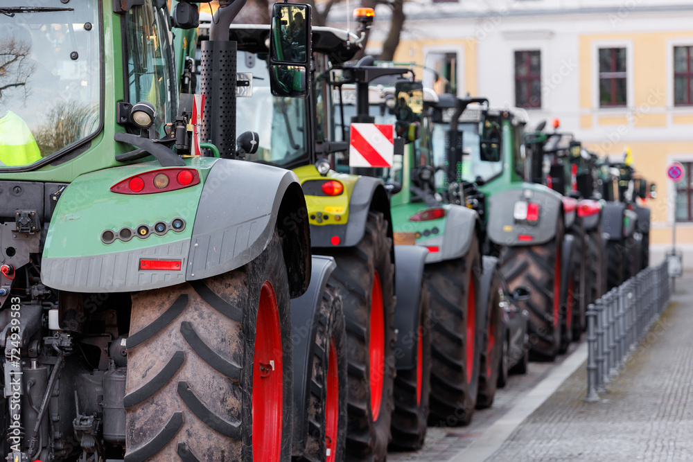Fototapeta premium Farmers union protest strike against government Policy in Germany Europe. Tractors vehicles blocks city road traffic. Agriculture farm machines Magdeburg central Domplatz square